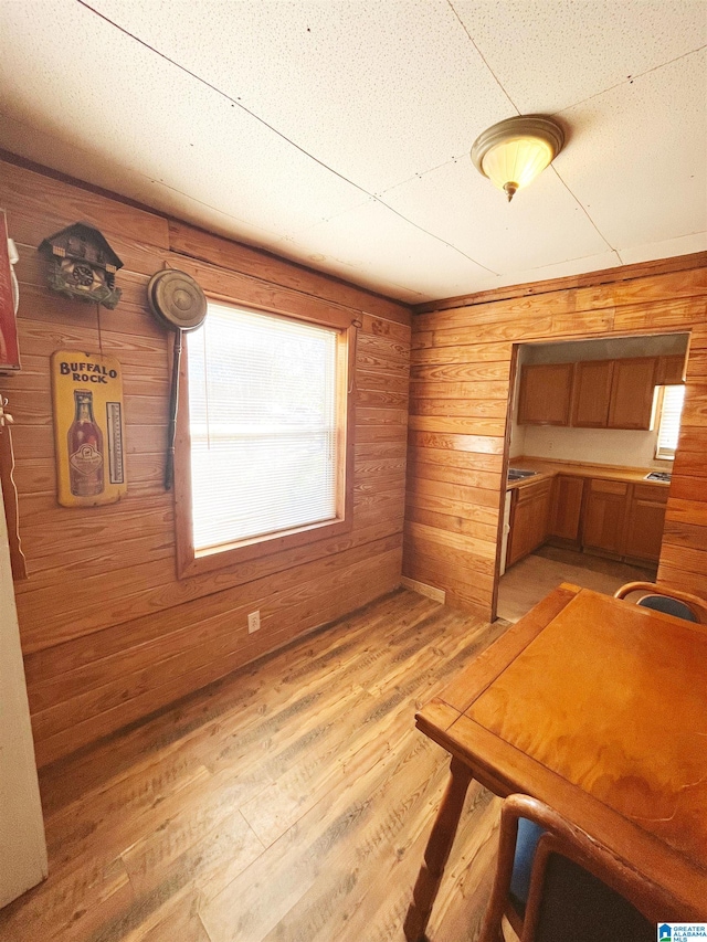 unfurnished dining area with light wood-type flooring and wooden walls