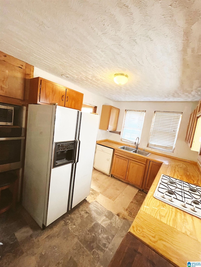 kitchen featuring a textured ceiling, sink, and white appliances