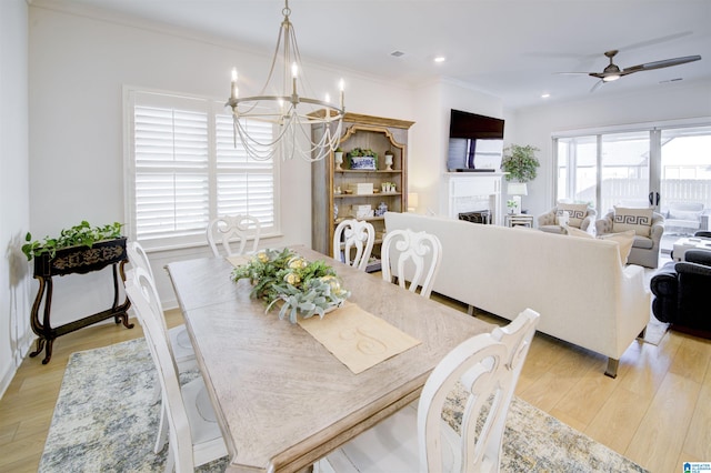 dining space with ceiling fan with notable chandelier, light hardwood / wood-style floors, and crown molding