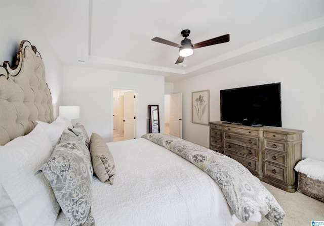 bedroom with carpet flooring, connected bathroom, a raised ceiling, and ceiling fan