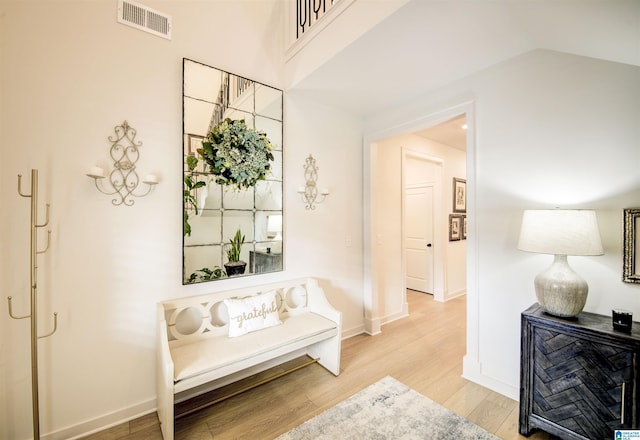 corridor with hardwood / wood-style floors and vaulted ceiling