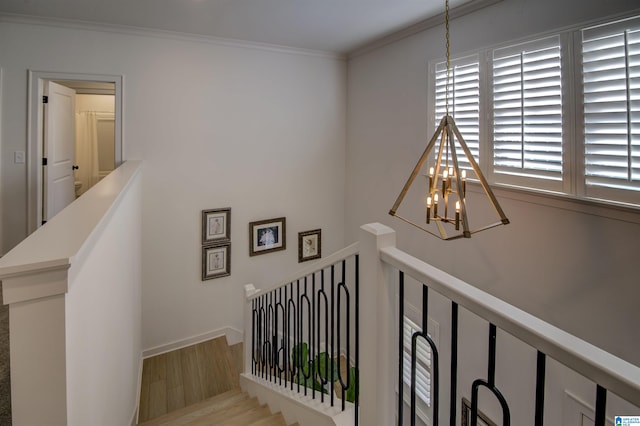 stairs with crown molding, wood-type flooring, and an inviting chandelier