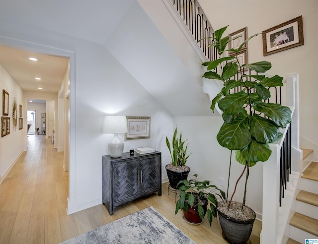 hallway with vaulted ceiling and light hardwood / wood-style flooring