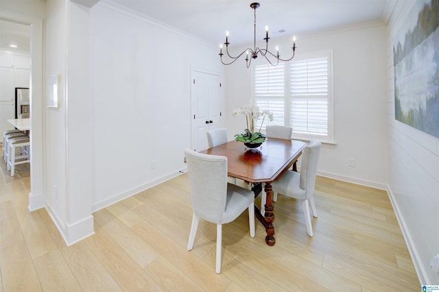 dining area with light hardwood / wood-style flooring, ornamental molding, and an inviting chandelier