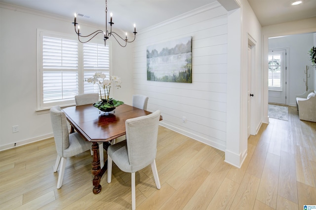 dining area with a notable chandelier, light wood-type flooring, and ornamental molding