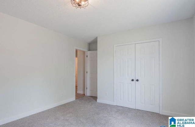 unfurnished bedroom featuring carpet flooring, a textured ceiling, and a closet