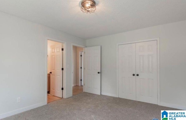 unfurnished bedroom featuring a textured ceiling, light colored carpet, and a closet