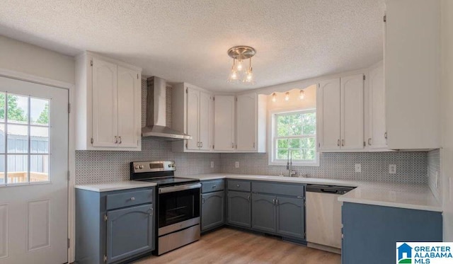 kitchen featuring wall chimney exhaust hood, white cabinetry, and stainless steel appliances