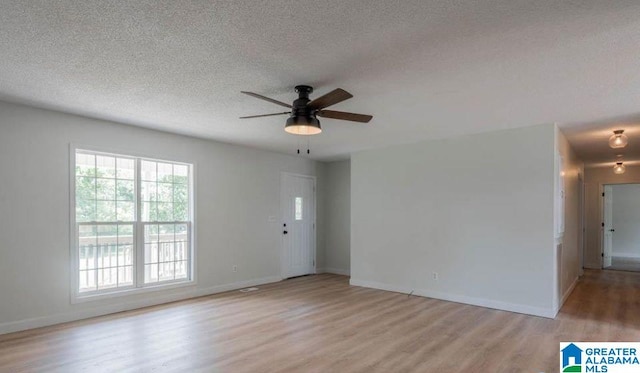 spare room featuring ceiling fan, light hardwood / wood-style flooring, and a textured ceiling