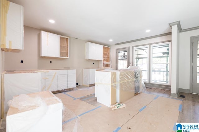 kitchen with light wood-type flooring, white cabinetry, and crown molding