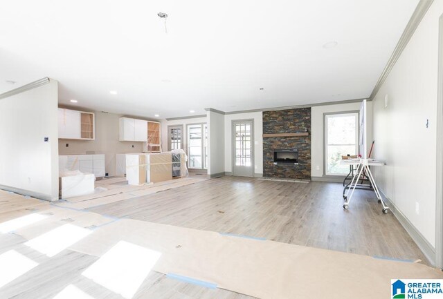 unfurnished living room with plenty of natural light, crown molding, a fireplace, and light hardwood / wood-style flooring