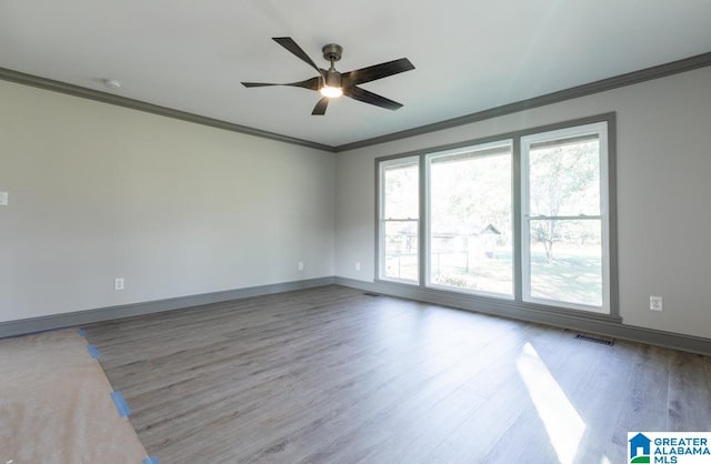 empty room featuring ceiling fan, hardwood / wood-style floors, and ornamental molding