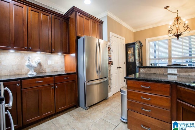 kitchen featuring dark stone counters, stainless steel appliances, crown molding, decorative light fixtures, and an inviting chandelier