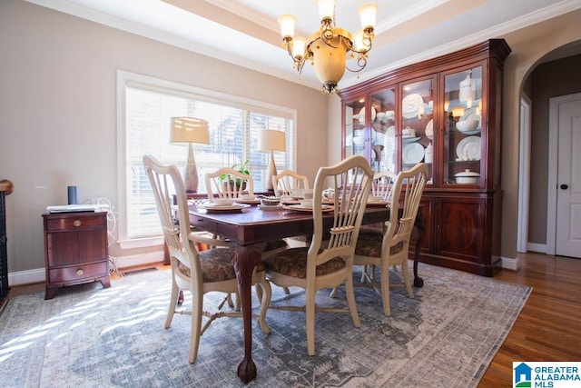 dining area with crown molding, dark hardwood / wood-style flooring, a healthy amount of sunlight, and a notable chandelier