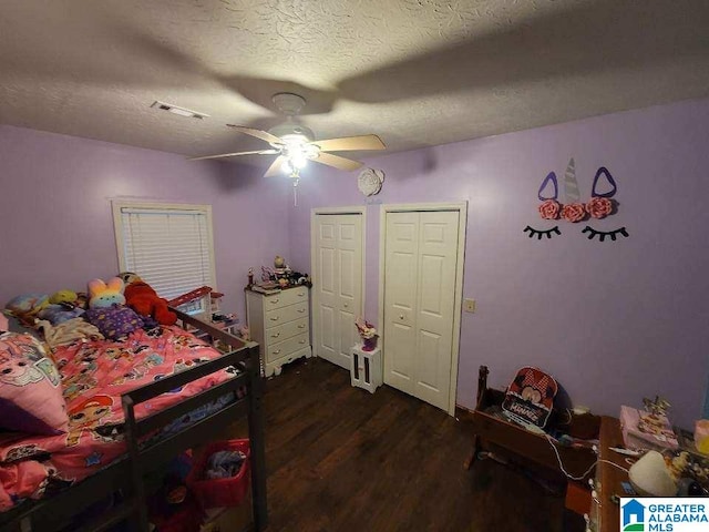 bedroom with a textured ceiling, dark hardwood / wood-style flooring, and ceiling fan