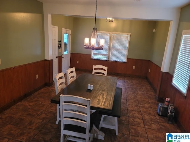 dining area featuring an inviting chandelier and wooden walls