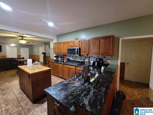 kitchen with ceiling fan, a kitchen island, light tile patterned floors, and tasteful backsplash