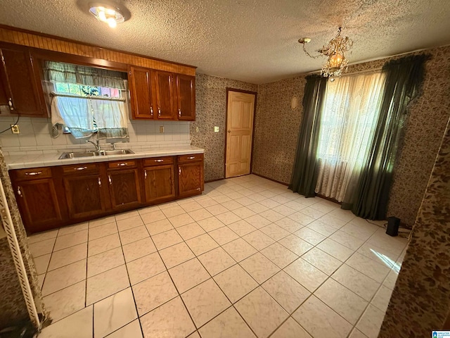 kitchen featuring a textured ceiling, decorative light fixtures, sink, and an inviting chandelier