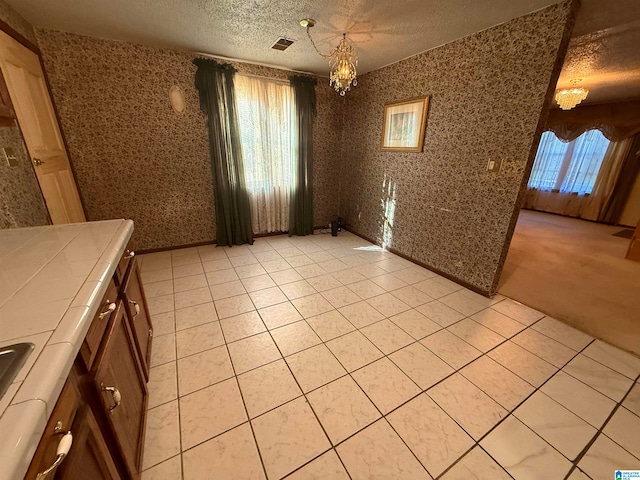 unfurnished dining area with a healthy amount of sunlight, light tile patterned floors, and a textured ceiling