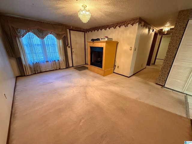 unfurnished living room featuring a notable chandelier, carpet floors, and a textured ceiling