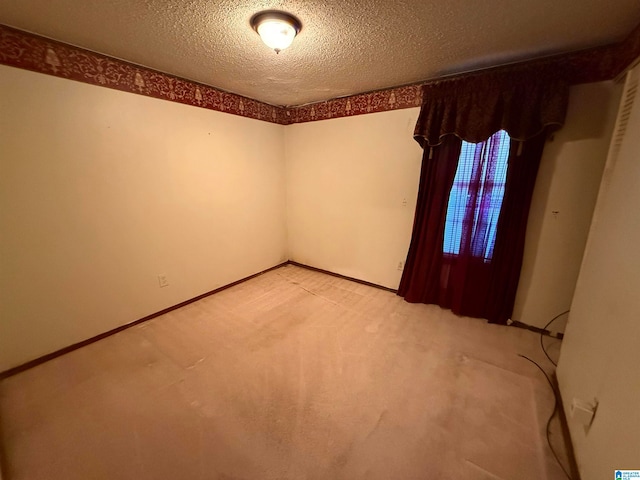 carpeted empty room featuring a textured ceiling