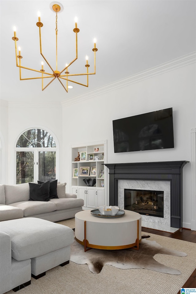 living room with hardwood / wood-style floors, a premium fireplace, ornamental molding, and a chandelier