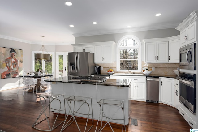 kitchen featuring white cabinets, dark hardwood / wood-style floors, decorative light fixtures, a kitchen island, and stainless steel appliances