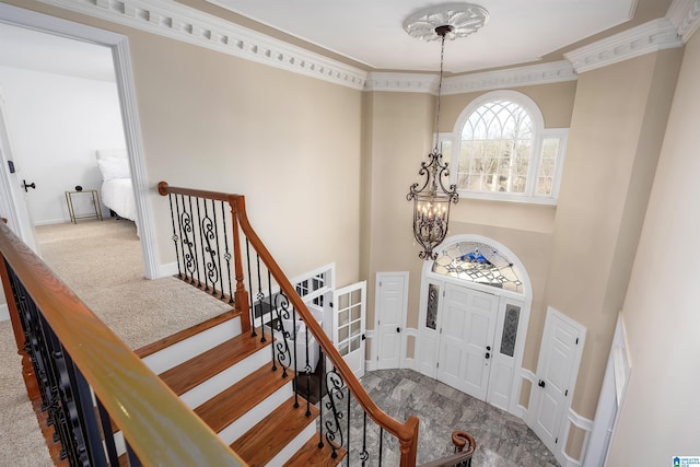 foyer entrance with a chandelier, carpet flooring, and crown molding