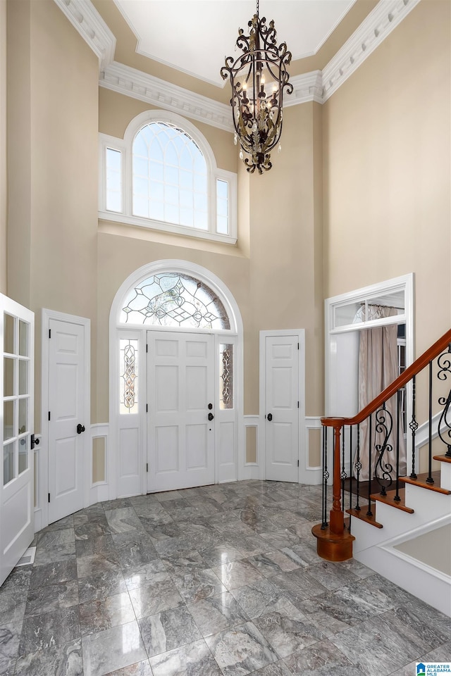 entryway with crown molding, a towering ceiling, and a healthy amount of sunlight