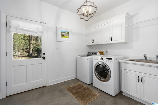 laundry area with washing machine and clothes dryer, sink, cabinets, a notable chandelier, and dark tile patterned flooring