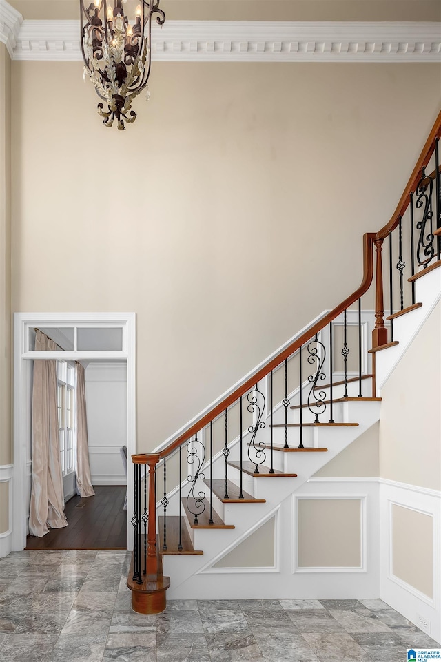 stairs featuring a notable chandelier, wood-type flooring, and ornamental molding