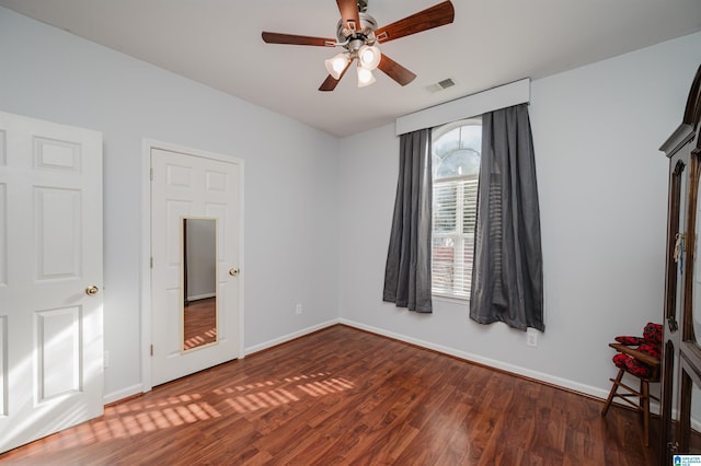 unfurnished bedroom with ceiling fan and dark wood-type flooring