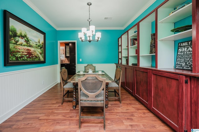 dining space featuring light hardwood / wood-style floors, an inviting chandelier, and crown molding