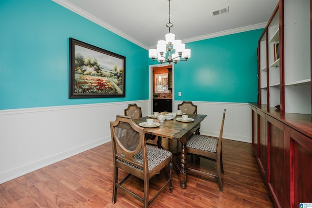 dining room with ornamental molding, a notable chandelier, and hardwood / wood-style flooring