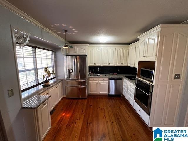 kitchen with dark hardwood / wood-style flooring, white cabinets, ornamental molding, and appliances with stainless steel finishes