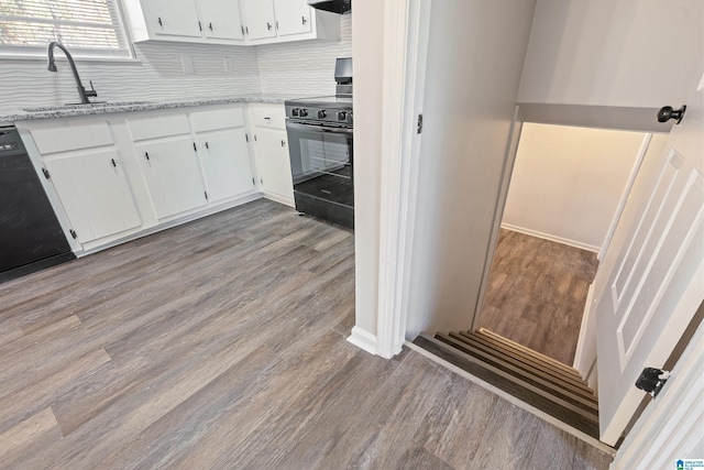 kitchen with black appliances, white cabinets, sink, tasteful backsplash, and light hardwood / wood-style floors