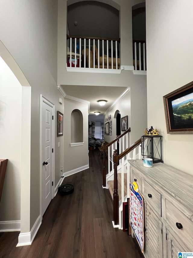 hallway with dark hardwood / wood-style flooring, crown molding, and a high ceiling