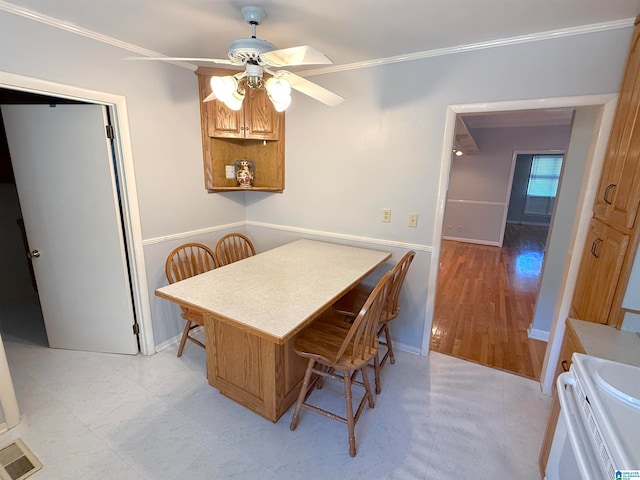 dining area with ceiling fan, crown molding, and light wood-type flooring