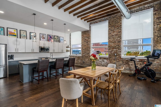 dining room with beamed ceiling, dark wood-type flooring, and brick wall