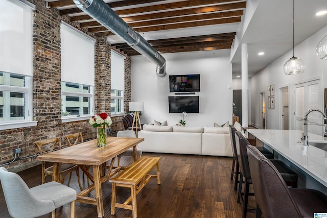 dining room featuring beam ceiling, sink, dark wood-type flooring, and brick wall