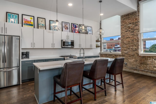 kitchen featuring dark hardwood / wood-style flooring, white cabinets, pendant lighting, and appliances with stainless steel finishes