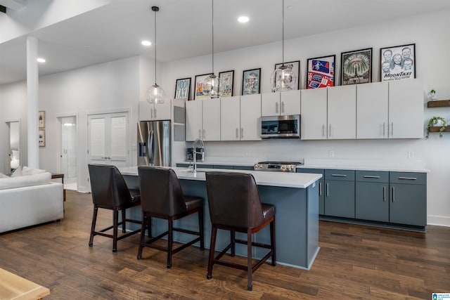 kitchen featuring stainless steel appliances, dark hardwood / wood-style floors, decorative light fixtures, a breakfast bar area, and white cabinets