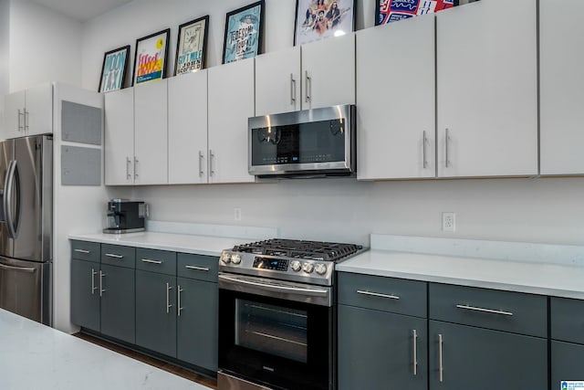 kitchen featuring gray cabinets, white cabinetry, and appliances with stainless steel finishes