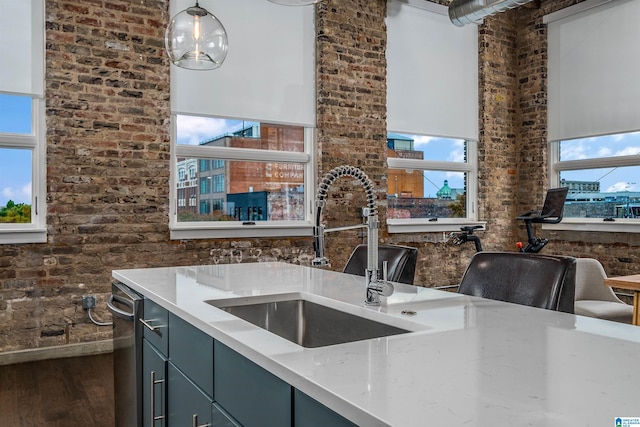 kitchen featuring brick wall, sink, blue cabinetry, hardwood / wood-style floors, and hanging light fixtures