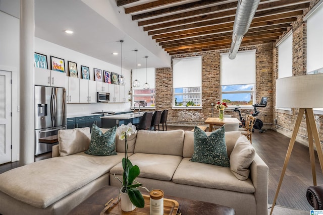 living room with beamed ceiling, hardwood / wood-style floors, a high ceiling, and brick wall