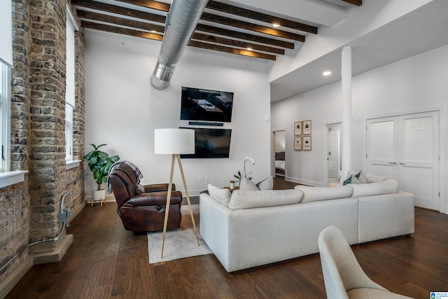 living room featuring beamed ceiling, dark wood-type flooring, and a high ceiling