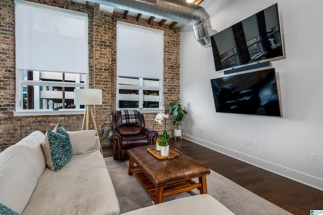 living room featuring a wealth of natural light, wood-type flooring, and brick wall