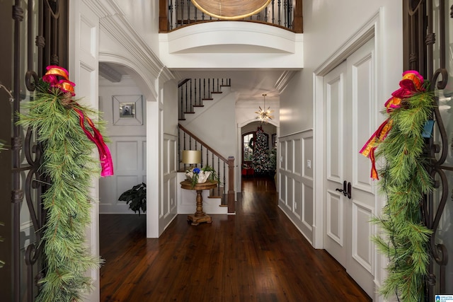 entrance foyer featuring crown molding, dark hardwood / wood-style flooring, and a towering ceiling