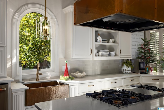 kitchen with appliances with stainless steel finishes, backsplash, island range hood, sink, and white cabinets