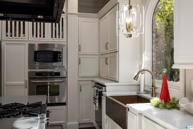 kitchen featuring white cabinetry, sink, stainless steel appliances, and a notable chandelier